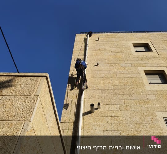 אדם מטפס על קיר בניין לצורך עבודת איטום